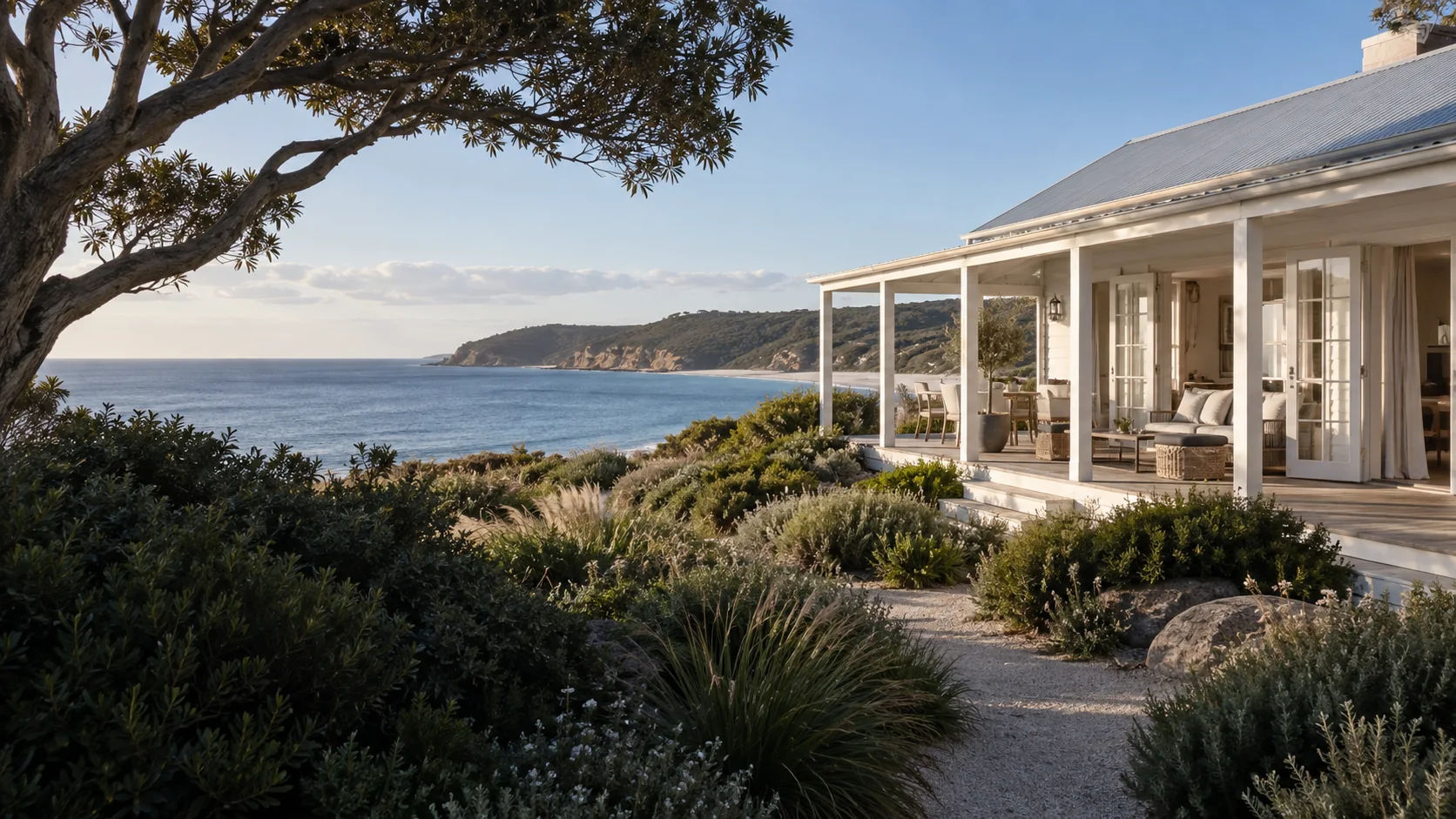 An imagined white weatherboard guesthouse above native dune gardens and calm coastal water